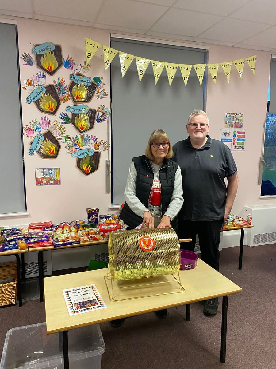 Two volunteers behind a golden tombola drum loaded with chocolate prizes